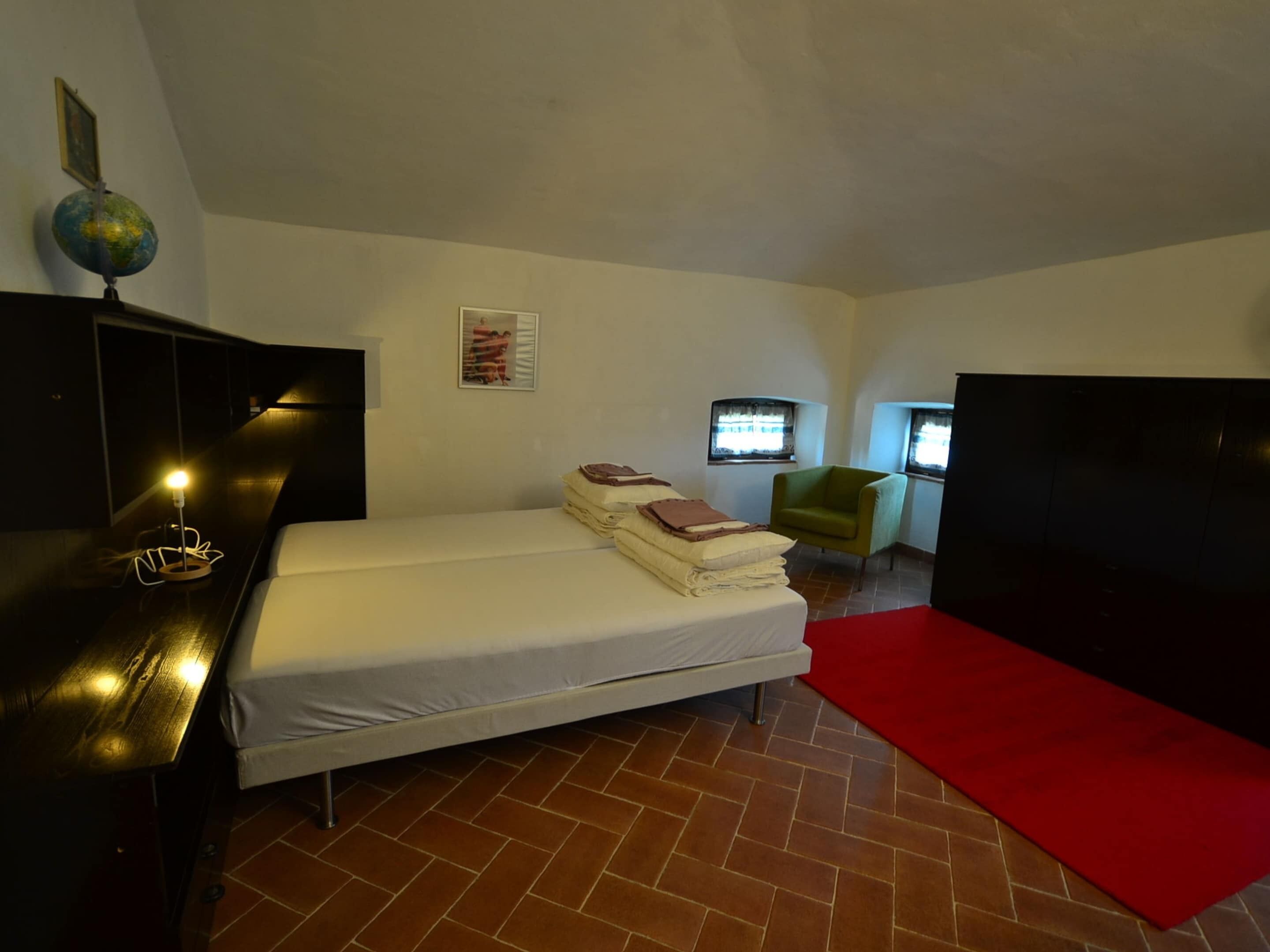A small, compact room with a single bed, a desk, a chair, and a globe on the wall.