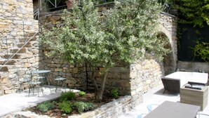 A stone building with outdoor seating, including tables and chairs, and a small tree in the center. - Rustic Tuscan Cottage (Fivizzano)