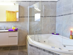 Une salle de bain moderne avec une douche à parois de verre, une baignoire blanche et un meuble-lavabo avec un miroir.