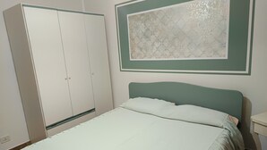 A bedroom with a bed, a wardrobe, and a decorative wall piece. - Lovely Holiday Home in Giardini Naxos near Sea (Taormina)