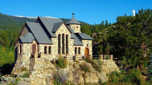 A stone church with a cross on top, surrounded by trees and a mountain in the background. - Cozy Garden Home in Erquy (Erquy)