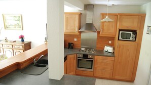 A kitchen with wooden cabinets, a microwave, a stove, and a sink. - Cozy Garden Home in Erquy (Erquy)