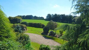 A lush green landscape with rolling hills, a gravel path, and dense shrubbery. - Cozy Garden Home in Erquy (Erquy)