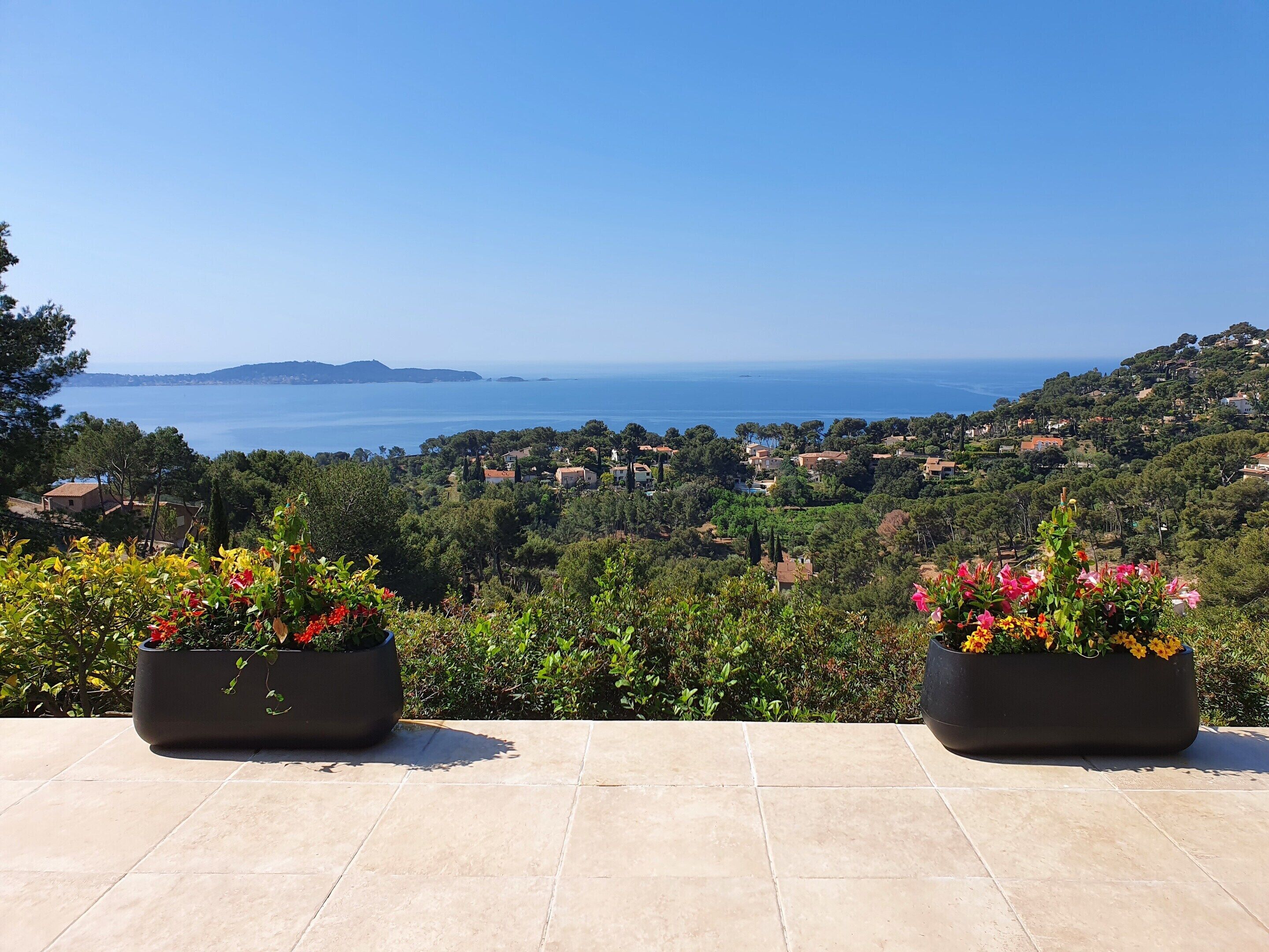 A terrace with potted plants and a view of a coastal town.