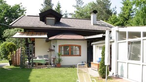 A house with a sloped roof, a covered patio, a lawn, and a garden. - Apartment in Wernberg in Carinthia With Pool (Wernberg)