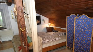 A cozy bedroom with a wooden ceiling, a bed with patterned bedding, a nightstand with a lamp, and a decorative blue screen. - Apartment in Wernberg in Carinthia With Pool (Wernberg)