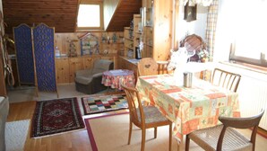 A cozy attic room with a dining table, chairs, a small sofa, and a wooden ceiling. - Apartment in Wernberg in Carinthia With Pool (Wernberg)