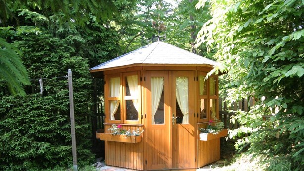 A wooden cabin with a peaked roof, large windows, and a small porch area with flower boxes. - Apartment in Wernberg in Carinthia With Pool (Wernberg)