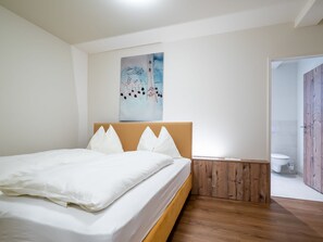 Un dormitorio con cama, paneles de madera, un cuadro en la pared y vista al baño.