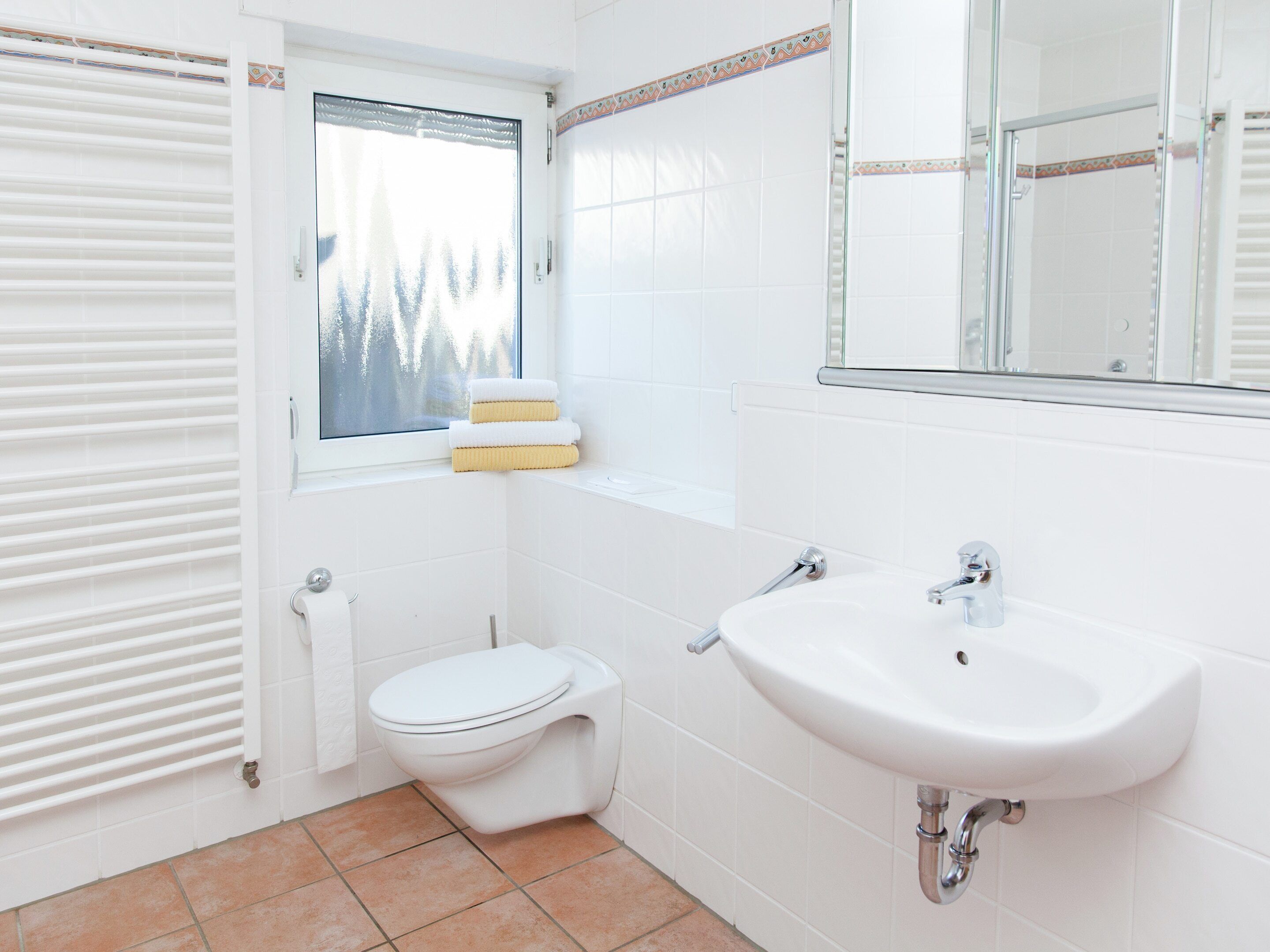 Une salle de bain avec des toilettes, un lavabo et une fenêtre.