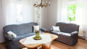 A living room with two grey sofas, a wooden coffee table, and a chandelier. - Spacious Holiday Home in Haserich near Lake (Haserich)