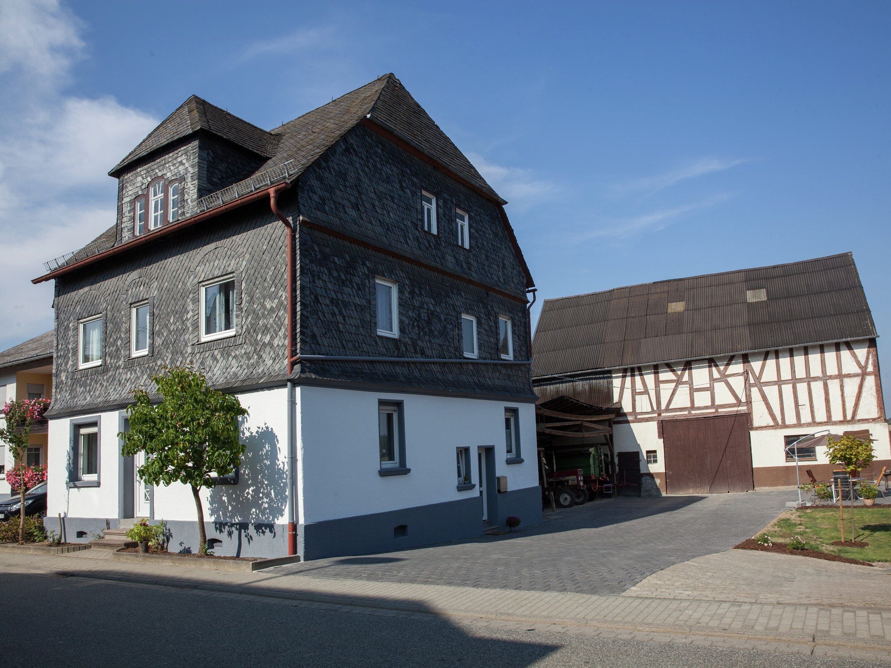 A two-story building with a steeply pitched roof, a white lower section, and a dark upper section.