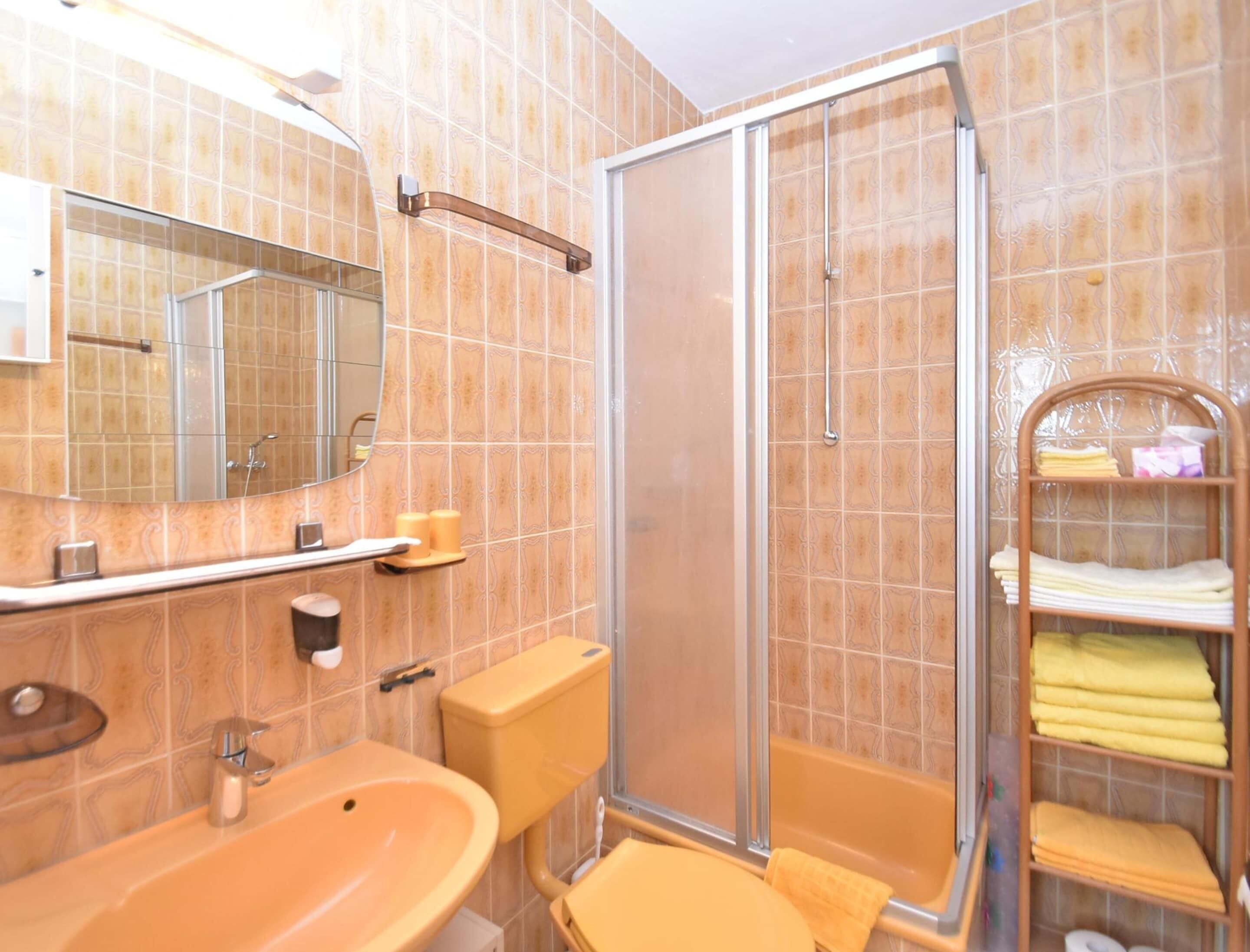 Une salle de bain équipée d’un lavabo, d’un miroir, de toilettes, d’une douche et d’un porte-serviettes.