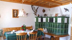 A dining area with wooden chairs, a table set with plates and cups, a green tiled wall, and a wooden ceiling. - Apartment in Sonnen Near Ski Lifts (Sonnen)