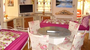 Una habitación acogedora con una cama, una mesa redonda, sillas con estampado floral, un televisor y un cuadro de un lago.