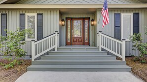 Ein Haus mit Veranda, Holztür und einer amerikanischen Flagge.