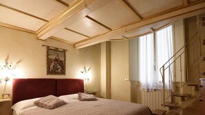 A bedroom with a large bed, a red headboard, two bedside lamps, a painting on the wall, and a staircase with a metal railing. - Apartment in Florence Near Duomo (Florence)