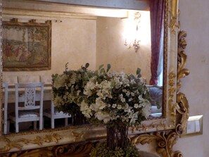 A mirror with a gold ornate frame, a white chair, and a vase with white flowers. - Apartment in Florence Near Duomo (Florence)