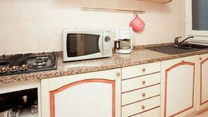 A kitchen with white cabinets, a microwave, a coffee maker, and a gas stove. - Apartment in Florence Near Duomo (Florence)