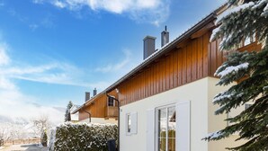 A wooden house with a balcony, a paved driveway, and snow-covered trees. - Chalet in Lungau With Sauna and hot tub (Sankt Margarethen im Lungau)