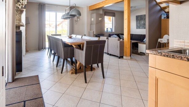 A spacious kitchen with a dining area, wooden beams, and a view of the outdoors. - Chalet in Lungau With Sauna and hot tub (Sankt Margarethen im Lungau)