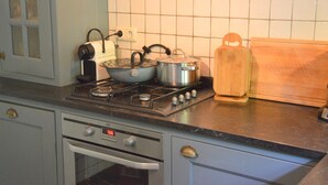 Eine Küche mit Herd, Töpfen, Wasserkocher und Schneidebrett.
