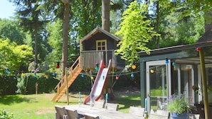 Eine Holzterrasse mit Bänken, einer Rutsche und einem Spielhaus.