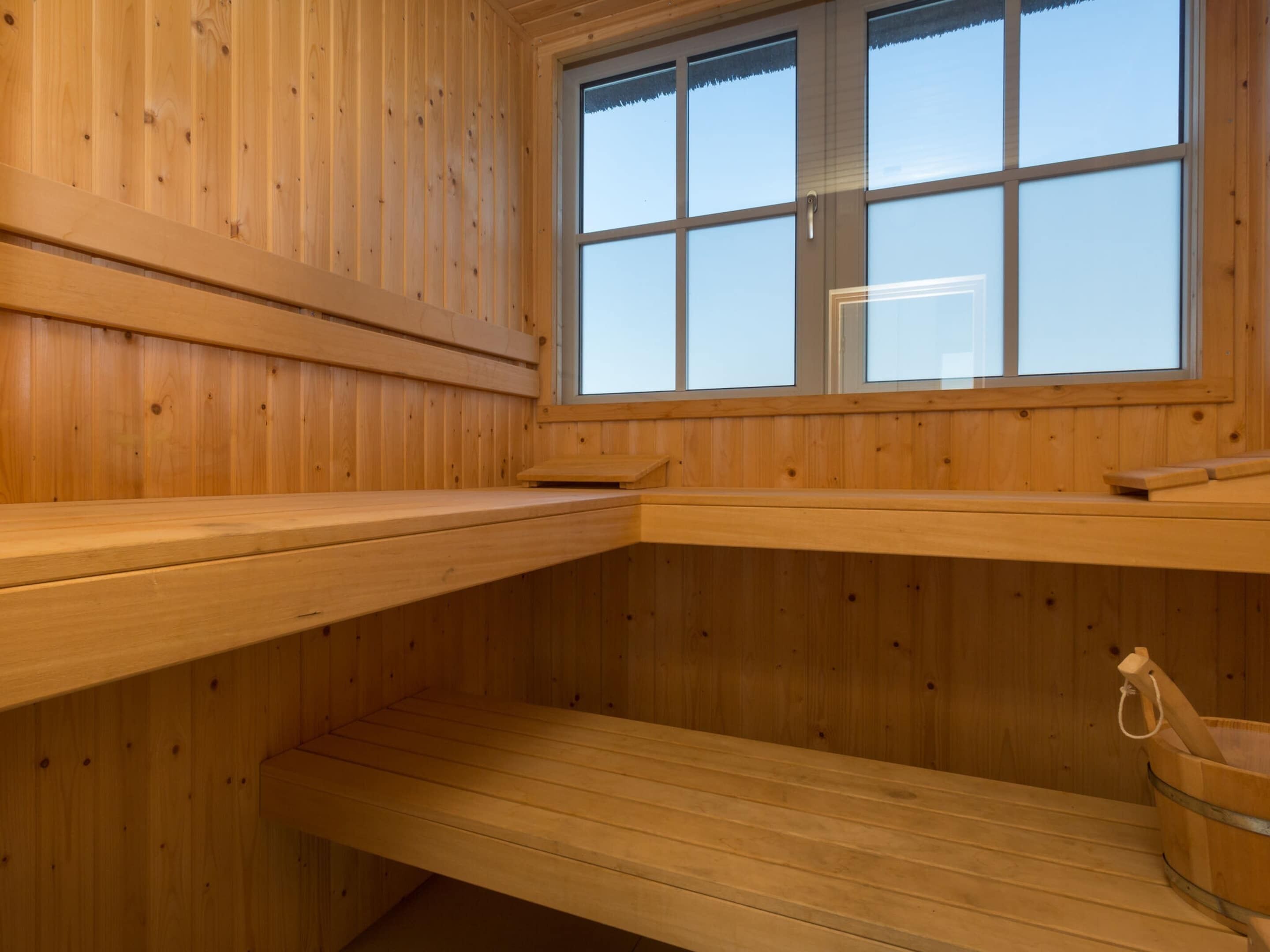 Un cuarto de sauna con bancos de madera y una ventana.