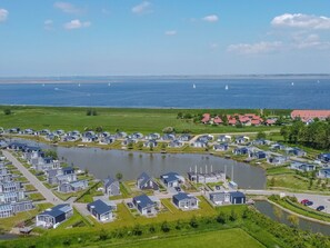 Un área residencial costera con casas modernas, un lago y veleros en el agua.