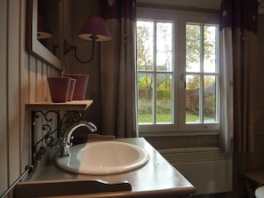 A bathroom with a white sink, a mirror, and a window with curtains. - Chalet in Forested Sourbrodt (Waimes)