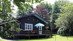 Une cabane en bois avec une véranda et un parasol bleu et blanc.