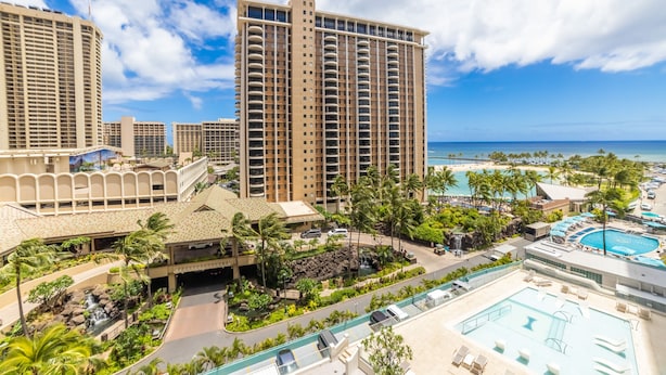 A resort with multiple high-rise buildings, a swimming pool, and a beach view.