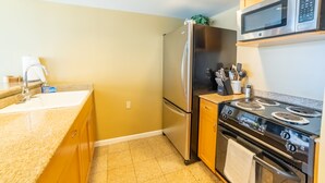 A kitchen with a stainless steel refrigerator, a microwave, a stove, and a sink.