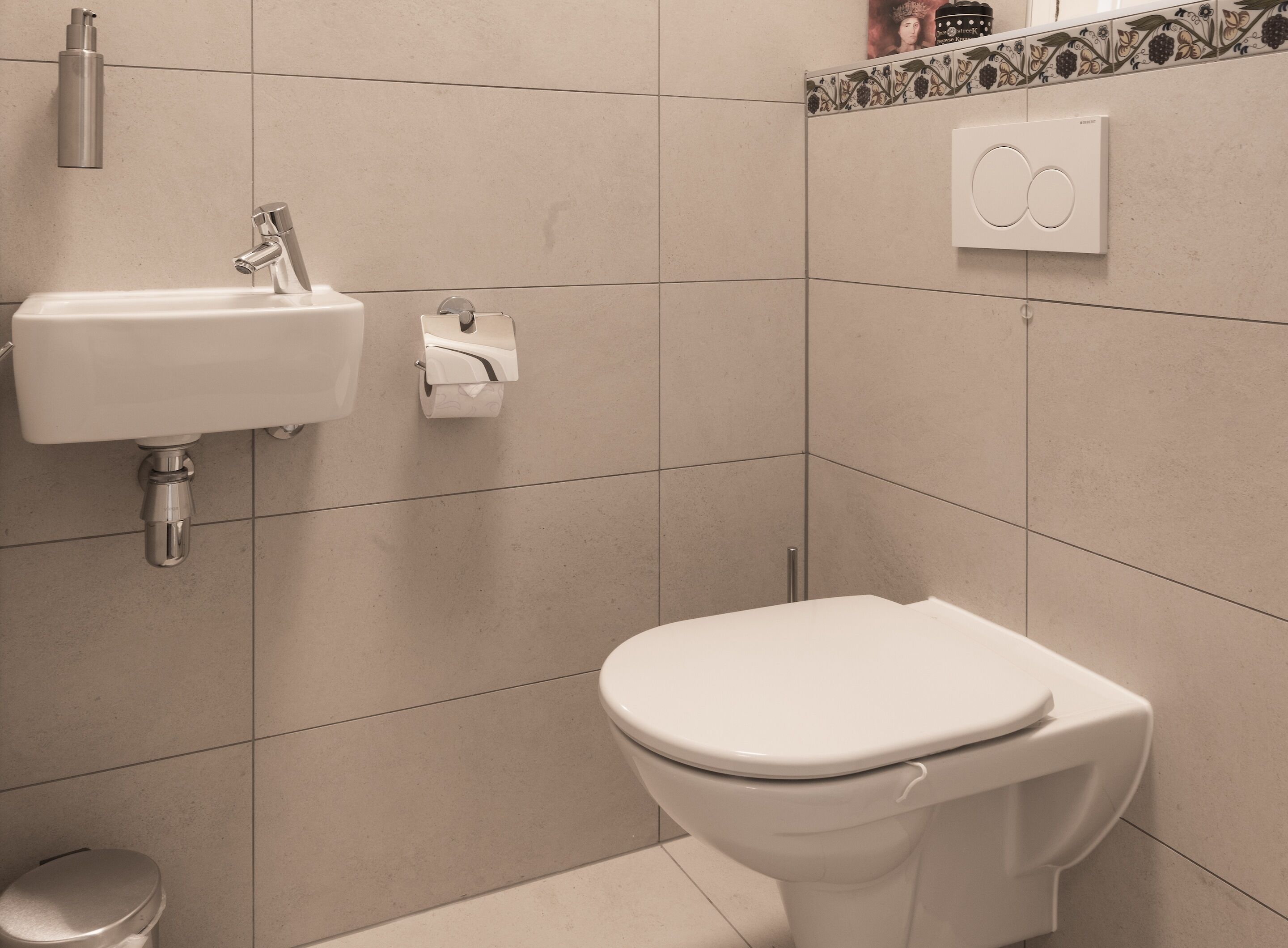 A bathroom with a toilet, sink, and toilet paper dispenser.