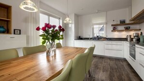 A modern kitchen with white cabinets, a wooden dining table, and green chairs. - Chic Villa With a Fireplace at Tjeukemeer (Delfstrahuizen)