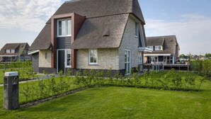 A modern house with a steeply pitched roof, brick exterior, and large windows. - Chic Villa With a Fireplace at Tjeukemeer (Delfstrahuizen)