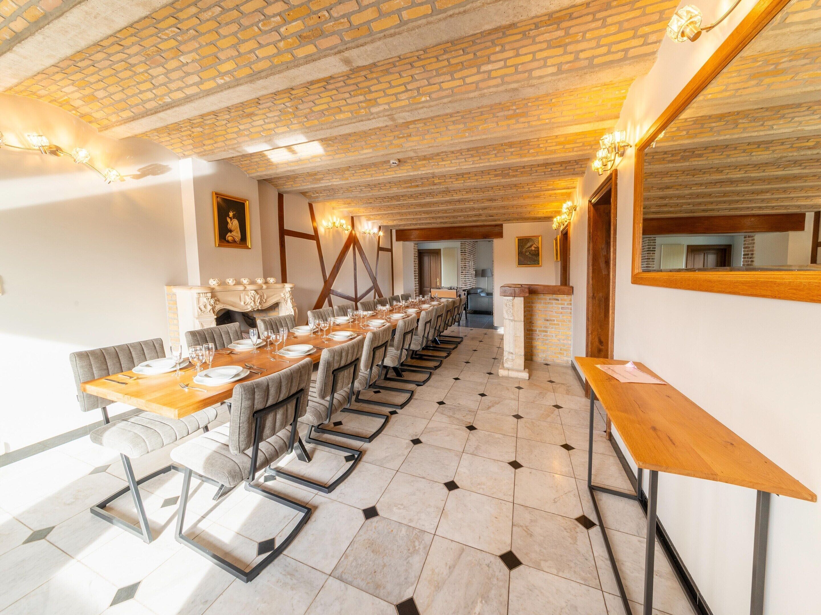 A long dining table set for a meal, with chairs and a mirror on the wall.