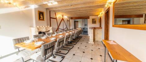 A long dining table set for a meal, with chairs and a mirror on the wall.