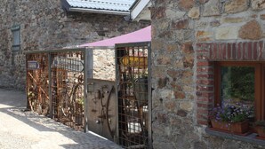 Un bâtiment en pierre avec un portail en métal et une fenêtre ornée de plantes en pot.