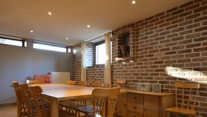 Un coin repas avec un mur en briques, des chaises en bois, une grande table et une radio intégrée.