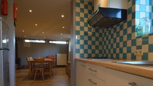 Une cuisine avec un crédence à carreaux, une cuisinière et un coin repas comprenant une table et des chaises.