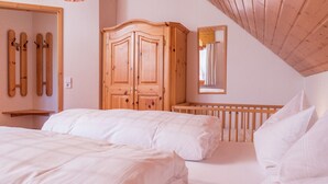 A bedroom with two beds, wooden wardrobe, and ski racks on the wall. - Lush Apartment in Furtwangen near Black Forest with Balcony (Furtwangen)
