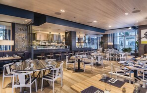 Enjoy meals in a stylish dining area with round and rectangular tables, a bar, and comfortable seating.