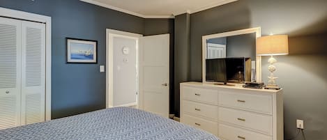 A bedroom with a bed, a dresser, a mirror, and a lamp.