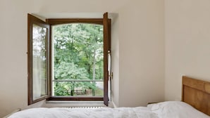 Un dormitorio con una cama, una ventana y vistas a árboles.