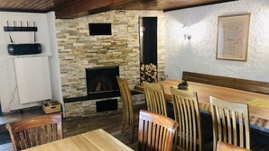 Un comedor acogedor con chimenea de piedra, sillas de madera y una mesa de madera.