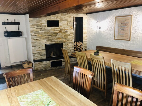 A cozy dining area with a stone fireplace, wooden chairs, and a wooden table. - Cozy Holiday Home In Brilon near Ski Slopes (Brilon)