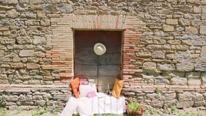 A stone wall with a rustic door, a small table with cushions, and a potted plant.