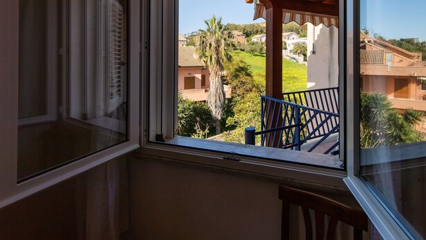 A room with a large window overlooking a residential area with houses and greenery. - A Sun-drenched Holiday Apartment Near the Sicilian Coastline (Sciacca)