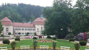 A large building with a red roof and multiple windows, surrounded by a well-maintained garden with benches and flower beds. - Nature & Wellness in Sohl (Bad Elster)